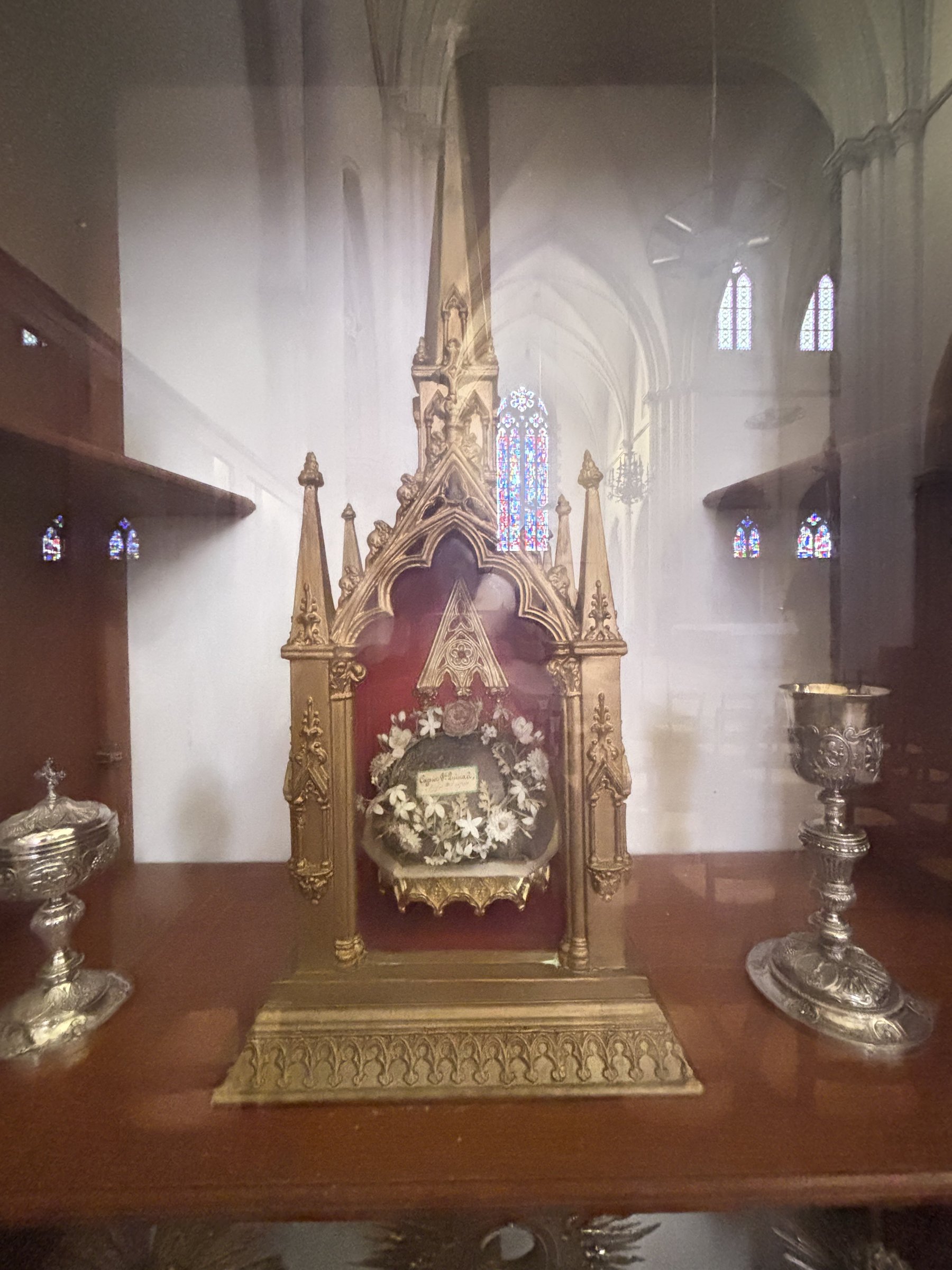 Het vergulde reliekschrijn van Saint Quay in de kerk, met glas-in-lood op de achtergrond.